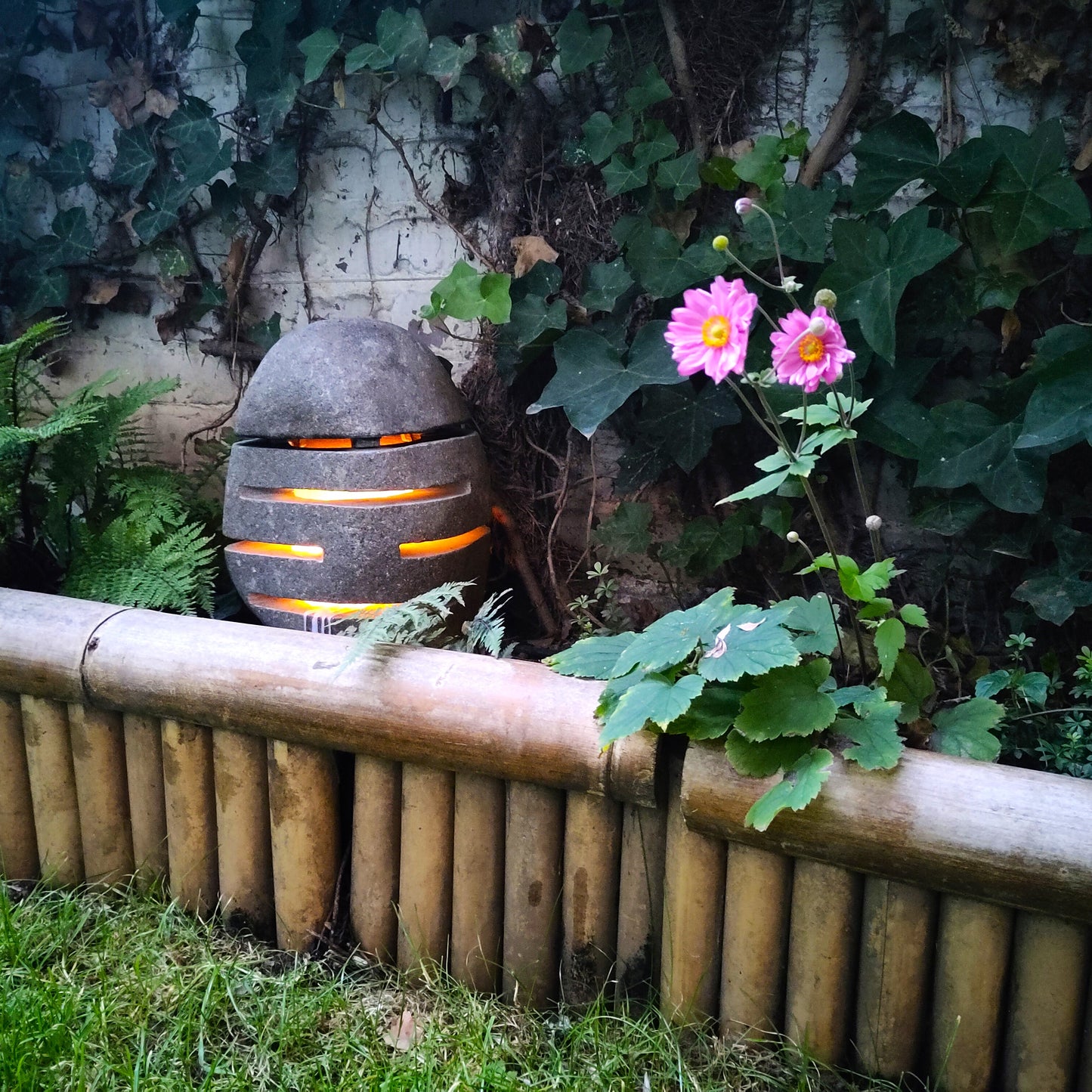 Leuchtende Steinlampe im Pflanzbeet.