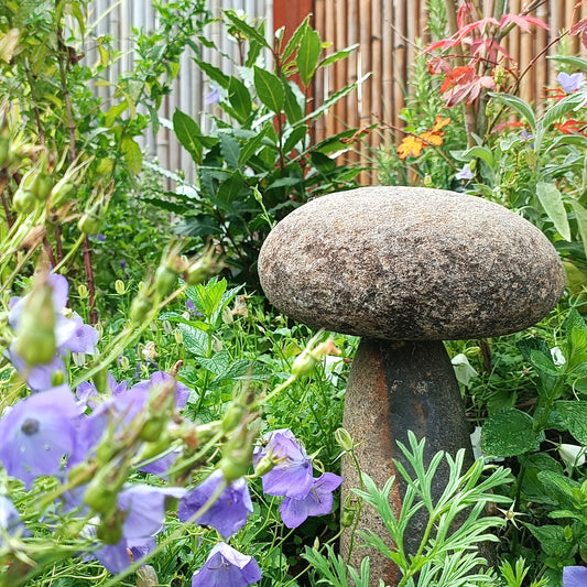Pilz aus indonesischem Flussstein im Gartenbeet.
