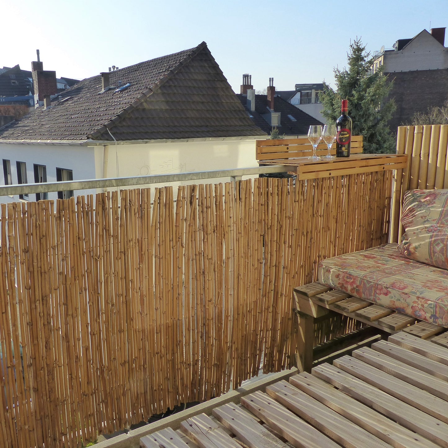 Dekorierter Balkon mit Sichtschutz aus Bambusstöcken.