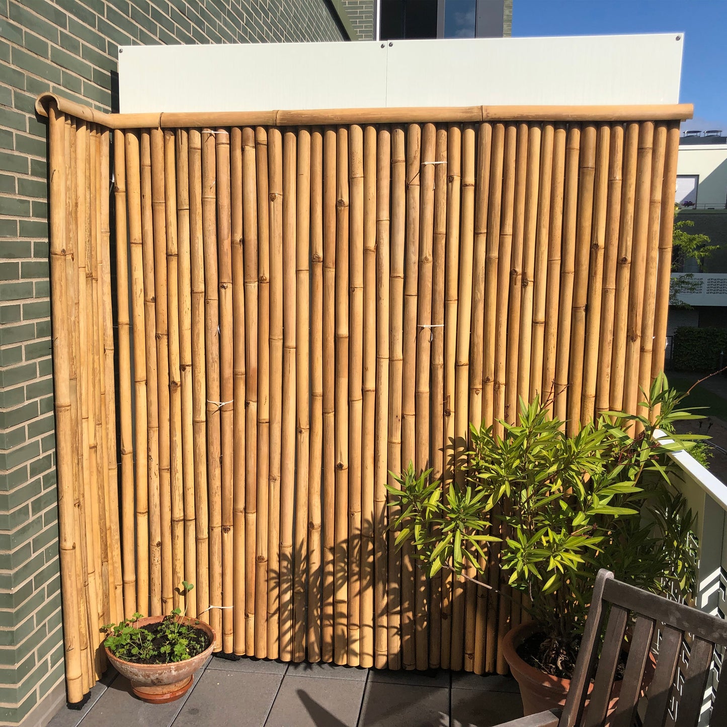 Balkonecke mit Bambus-Rollmatte zur Wandverkleidung mit einem Dreiviertel-Bambusrohr als Zaunabdeckung